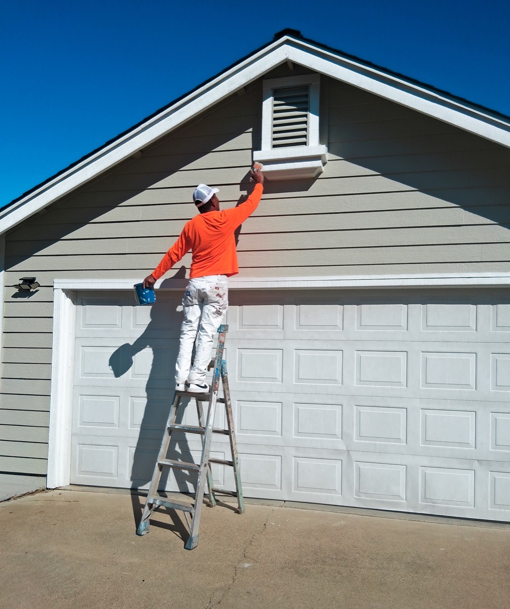 Painter on ladder working on garage trim Northern California